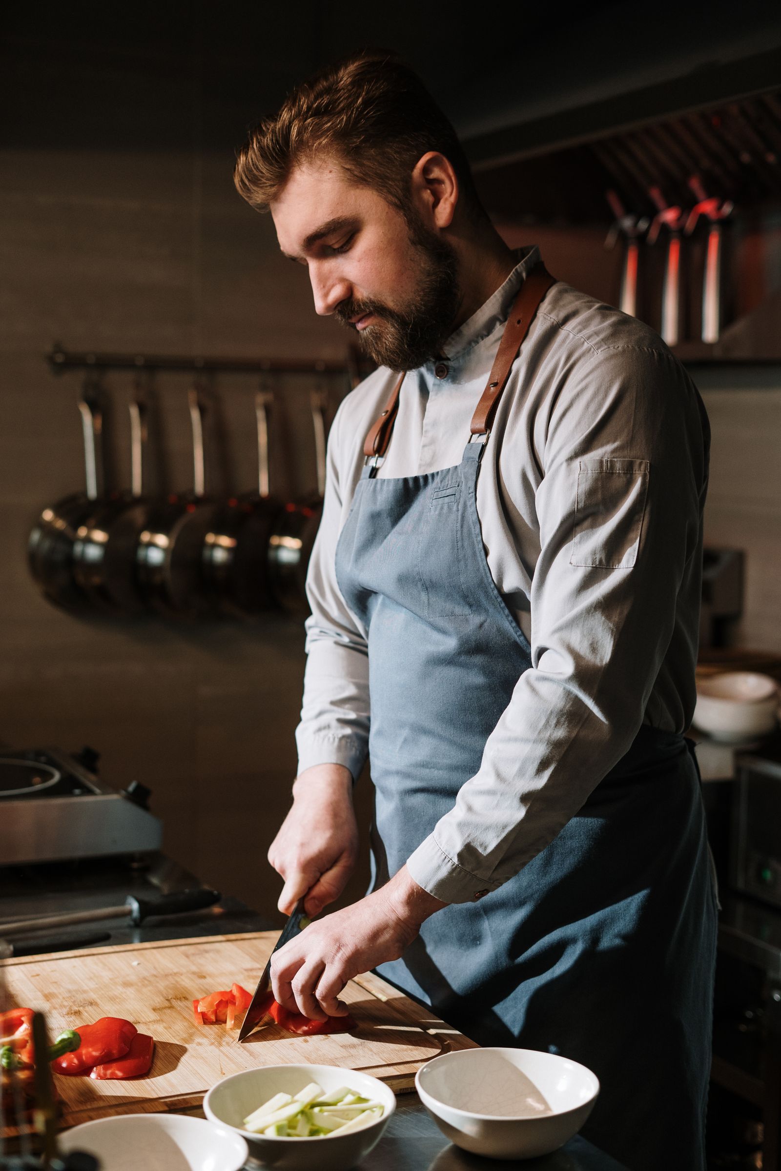 Chef preparing ingredients with commercial pans hanging behind